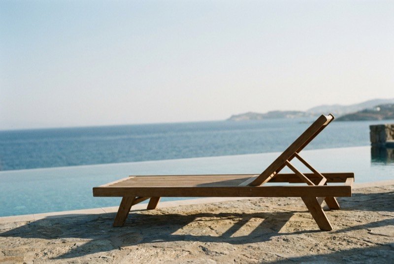 A sun lounger by an infinity pool at dusk